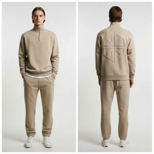 A full beige tracksuit with a quarter-zip collared sweatshirt and tapered sweatpants, distinguished by the large, embossed geometric logo on the back of the top.