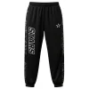 Front view of black warm-up pants with an elastic waistband, featuring a white and black outlined "STARS" logo on the left leg and a subtle geometric camo print on the side stripes.