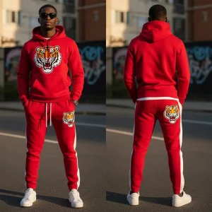 A bold red tracksuit featuring a hoodie and matching pants with white side stripes, embellished with chenille embroidered tiger graphics on the chest and the back of the joggers.