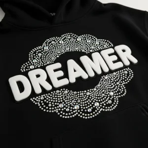 Closeup of a custom-made hoodie with puff print text "DREAMER" and rhinestones around it.