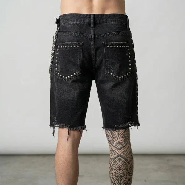 Back view of heavyweight denim jorts embellished with metallic studs and decorative side chains for a punk-inspired look.