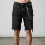 Front view of heavyweight denim jorts embellished with metallic studs and decorative side chains for a punk-inspired look.