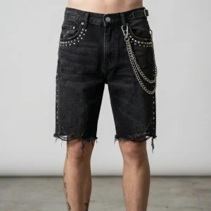Front view of heavyweight denim jorts embellished with metallic studs and decorative side chains for a punk-inspired look.