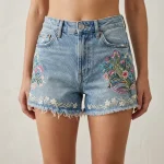 Custom denim shorts featuring colorful intricate floral embroidery on the front.