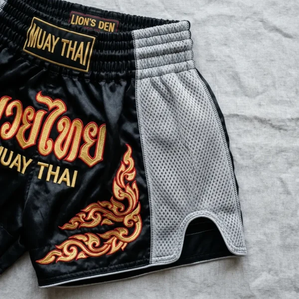 Black embroidered muay thai shorts with grey side mesh panels.
