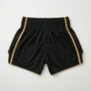 Back view of black satin Champion Leo Muay Thai shorts showcasing a large, vibrant gold and red embroidered dragon on the right leg.