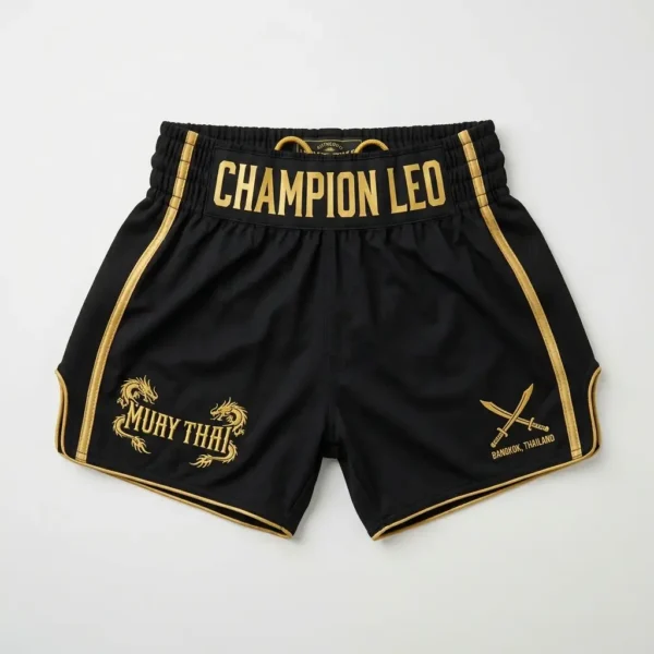 Front view of black Champion Leo kickboxing shorts featuring a detailed gold dragon embroidery, red piping, and gold bold lettering.