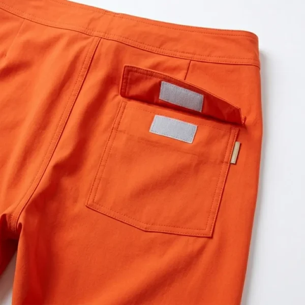 Velcro back pocket closeup on orange board shorts.
