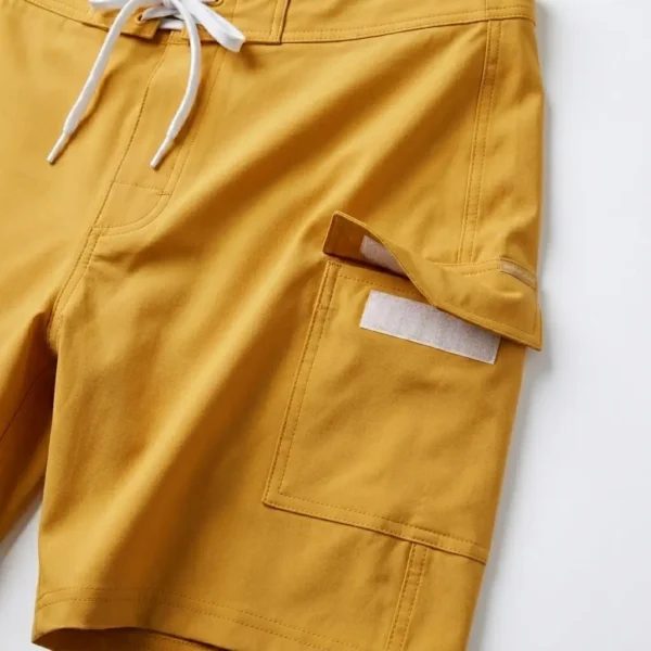 Velcro side pocket closeup on yellow board shorts.