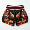 Back view of black Victoria Fight Club Muay Thai shorts featuring a large orange roaring tiger graphic and traditional golden side patterns.
