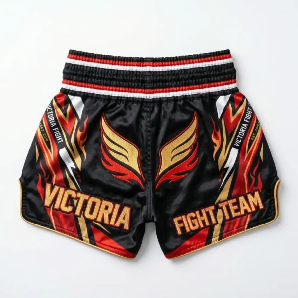 Back view of black Victoria Fight Club Muay Thai shorts featuring a large orange roaring tiger graphic and traditional golden side patterns.