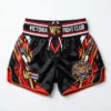 Front view of black Victoria Fight Club kickboxing shorts with an orange tiger graphic, gold waistband text, and red side accents.
