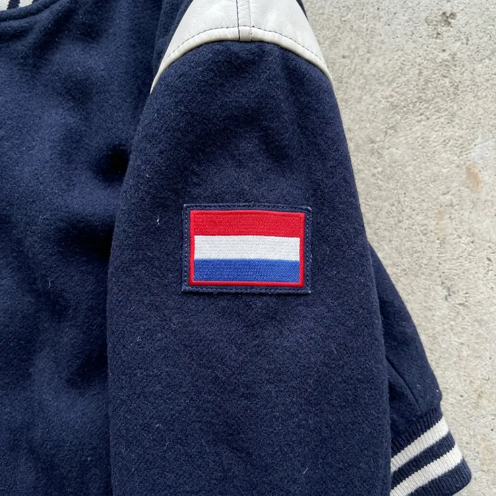 Embroidered flag patch on varsity jacket sleeve.