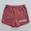 Front view of custom embroidered booty shorts in pink color with text embroidered on it.