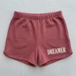 Front view of custom embroidered booty shorts in pink color with text embroidered on it.