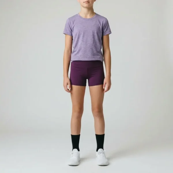 A young girl standing straight and wearing a purple heather t-shirt with custom purple booty shorts.