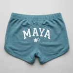 Light teal custom rhinestone booty shorts back with screen printed text and rhinestones around it.