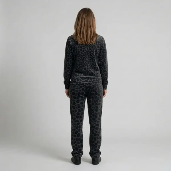 Back view of a woman wearing black charcoal spotted animal print velour tracksuit.