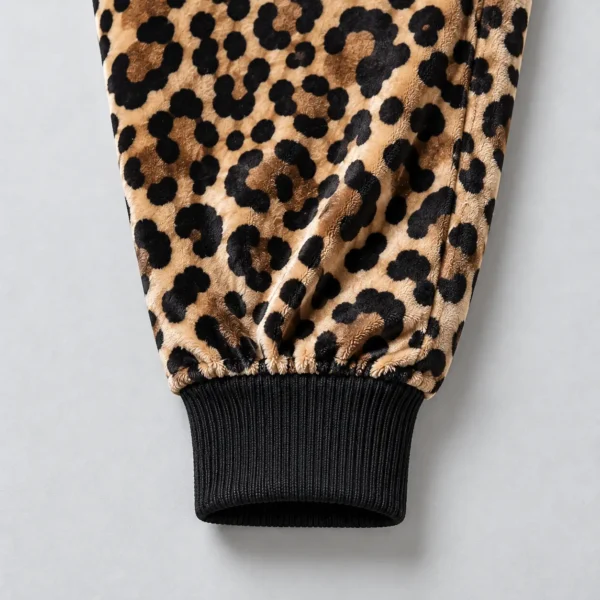 Close up of ribbed ankle of a leopard printed velour track pants.