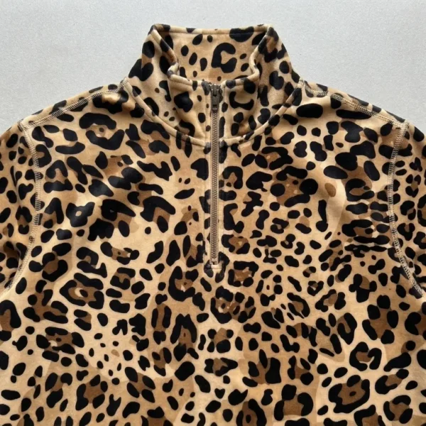 Closeup view of a caramel cream quarter zip leopard print velour track jacket.