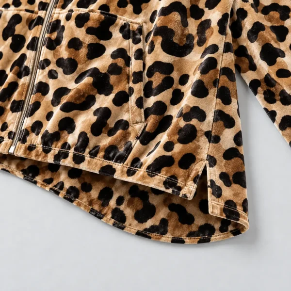 Closeup view on the hem of an all-over-printed leopard design dropped back hem velour track jacket.