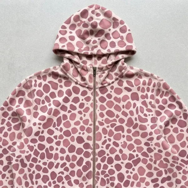 A closeup view of dusty rose spotted animal print hooded velour track jacket.