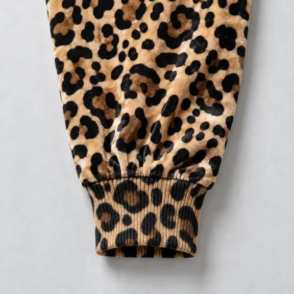 Close up of printed ribbed cuff of a leopard printed velour track jacket.