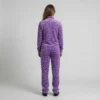 Back view of a woman wearing purple spotted animal print velour tracksuit.