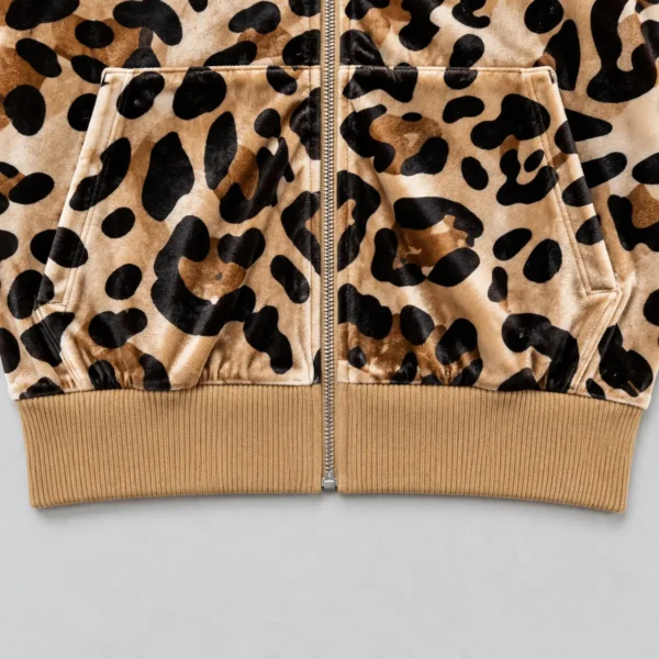 Closeup of bottom of a leopard printed velour track jacket with ribbed waistband.