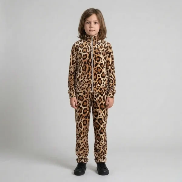 A kid is standing and wearing caramel brushstroke leopard print velour tracksuit.