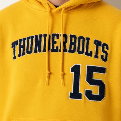 flock-screen-printed-hoodie-closeup Yellow hoodie with navy blue "THUNDERBOLTS 15" text using a raised, fuzzy flock screen printing technique. Shows detail of the print texture.