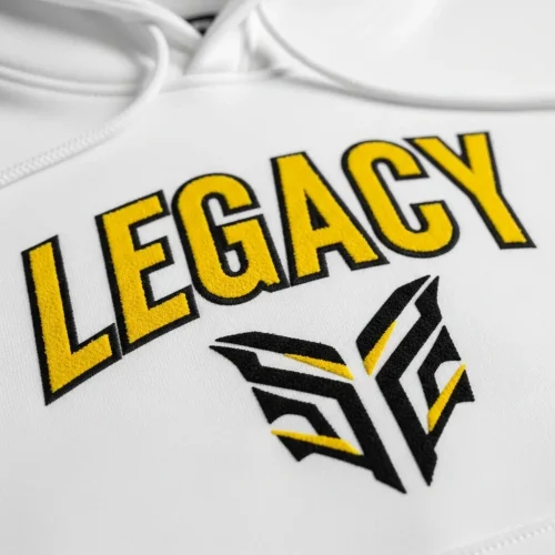 suede-screen-printed-hoodie White hoodie featuring a logo and the word "LEGACY" in yellow and black, demonstrating the soft, velvety texture of suede screen printing.